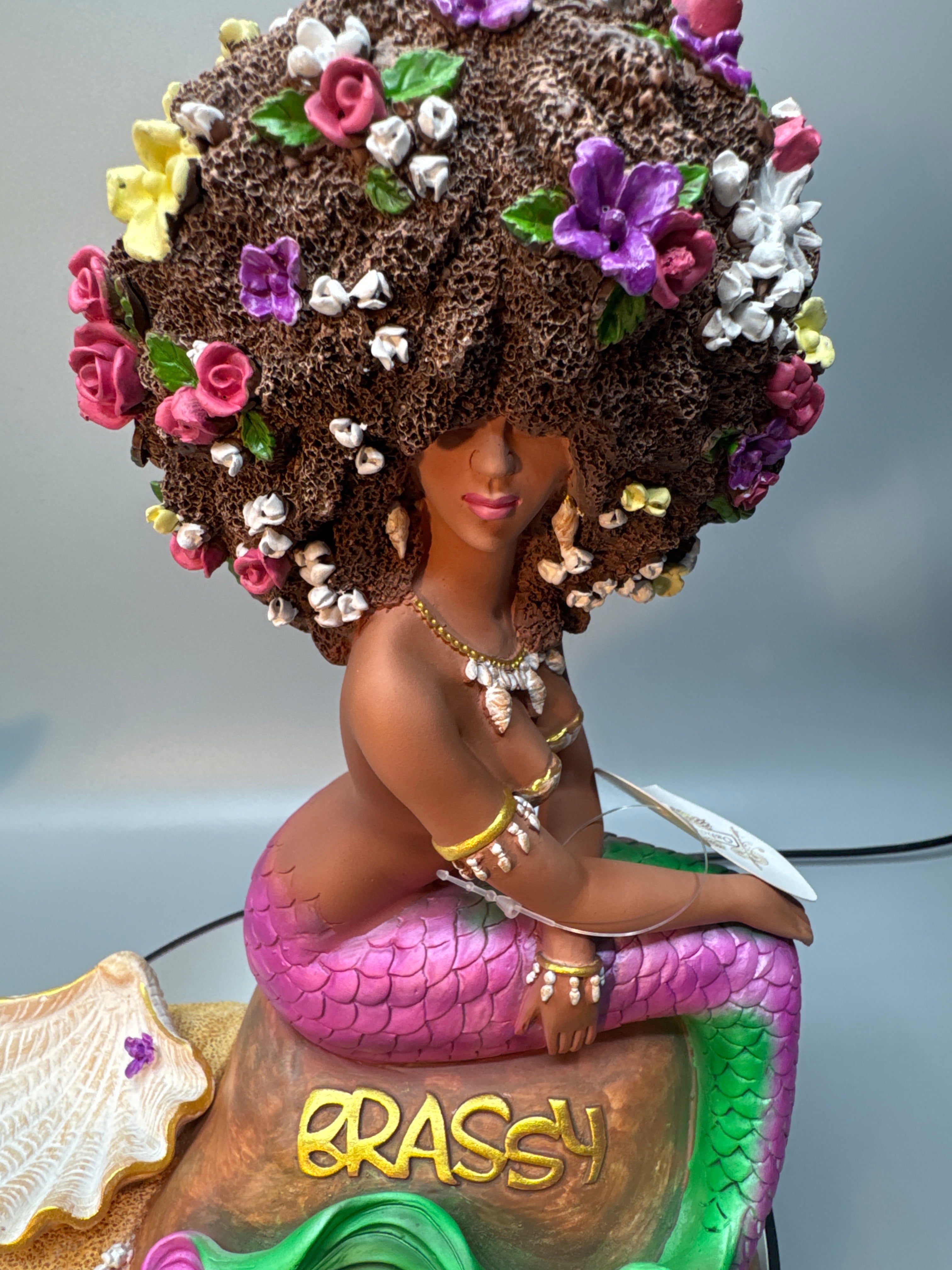 Close-up of Brassy’s richly textured afro decorated with colorful flowers nestled in her curls.