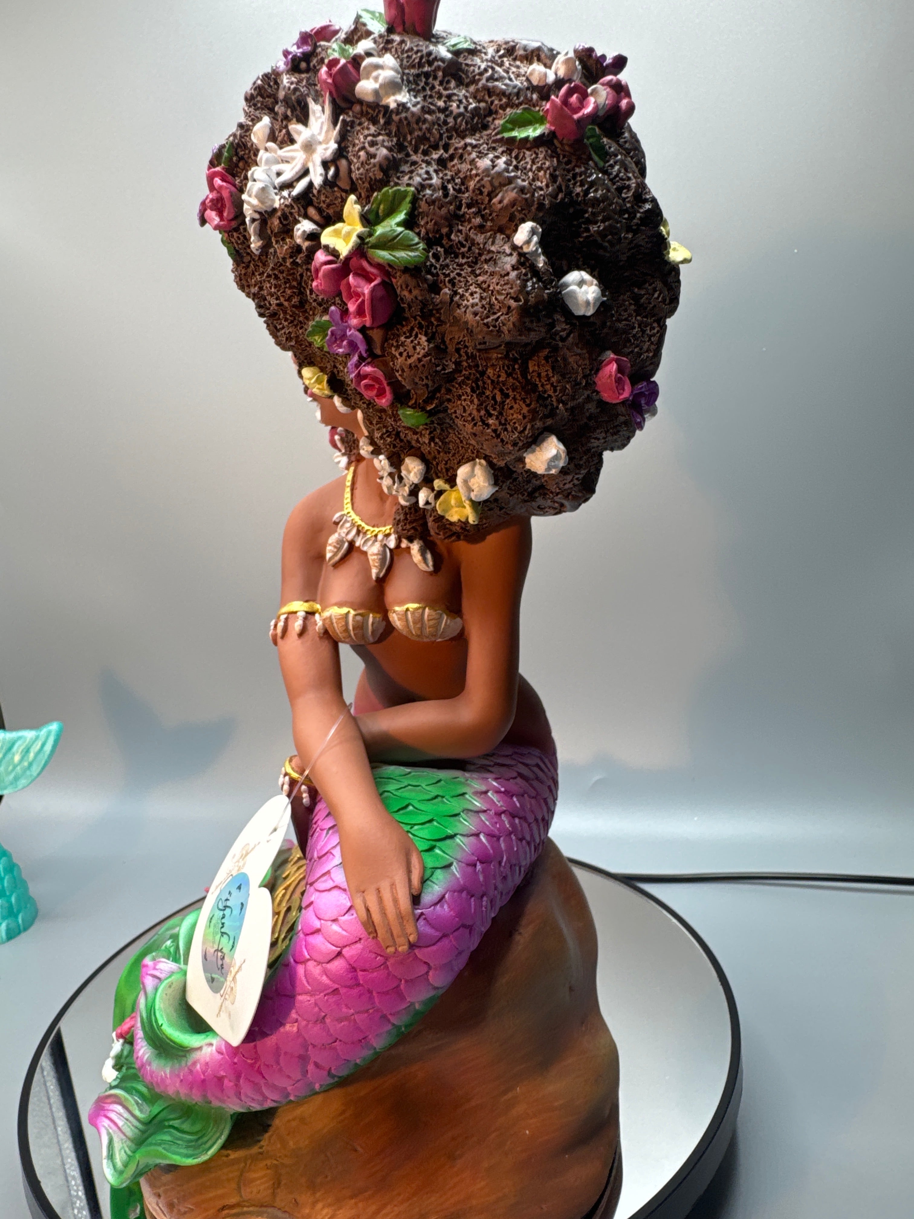 Back view of the Afro Mermaid statue showing her voluminous floral afro, detailed tail sculpt, and vibrant hand-painted flowers and scales.
